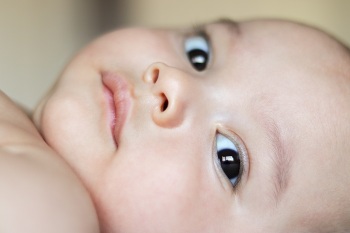 A baby laying down with beautiful brown eyes